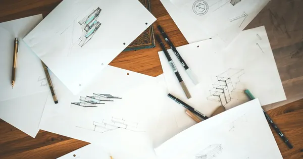 Dessins au crayon et feuilles d'animation éparpillés sur une table en bois, avec des stylos