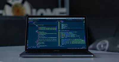 Ordinateur portable ouvert sur une table, affichant du code dans un éditeur sombre