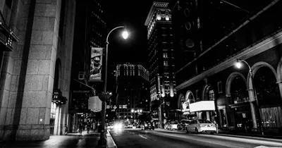 Night city street in black and white, a streetlamp and building fronts with dark arcades