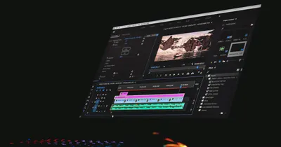 Logiciel de montage vidéo sur écran dans une pièce sombre, avec une timeline et une prévisualisation de paysage
