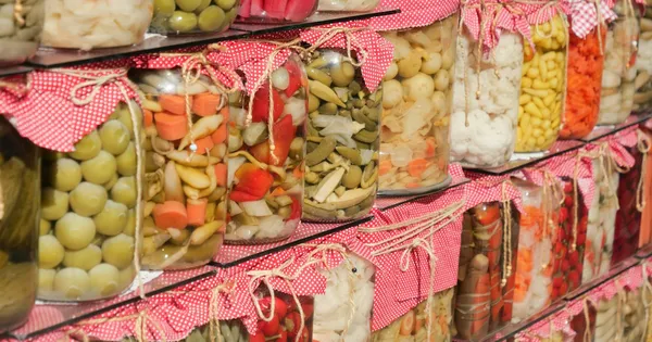 Bocaux en verre remplis de légumes et de baies marinés, fermés par des tissus à carreaux rouges