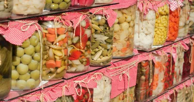 Bocaux en verre remplis de légumes et de baies marinés, fermés par des tissus à carreaux rouges