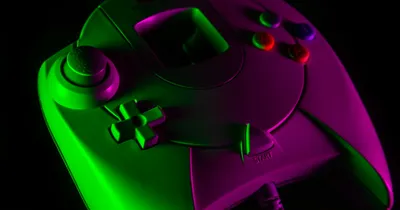 Manette de jeu vidéo verte et violette éclairée au néon sur fond noir