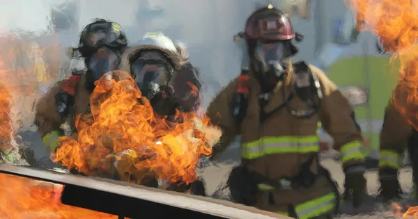 Pompiers casqués et masqués en exercice, avançant à travers des flammes orange dans une fumée grise