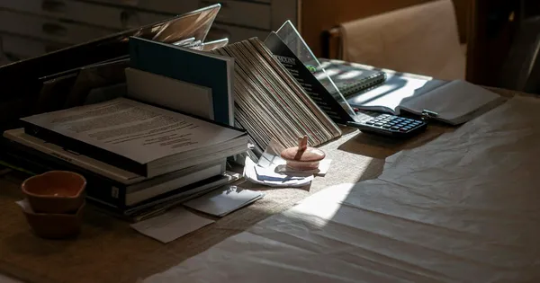 Bureau encombré de livres, de classeurs et de documents empilés
