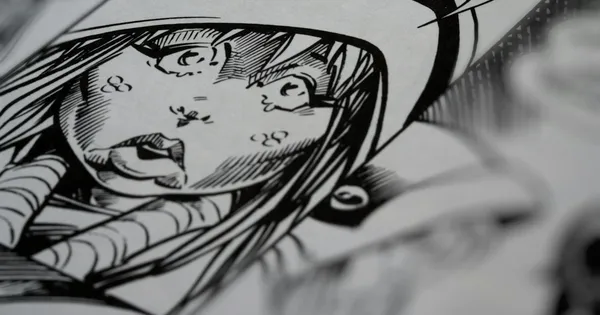 Planche de manga en cours d'encrage sur une table de travail encombrée