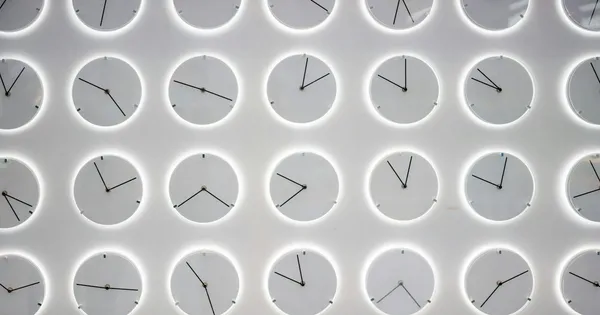 Grille de cadrans d'horloge blancs dans des disques clairs, aiguilles placées différemment